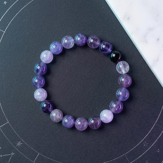 Purple beaded bracelet on a dark surface with star patterns