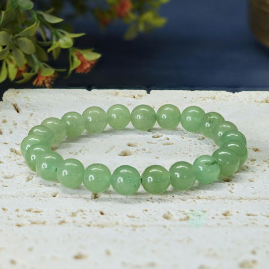 Green aventurine bracelet on a textured surface with a natural background